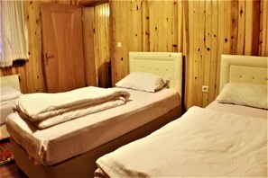 A room with two beds, wooden walls, and a door. - Yaren Otel (Çaykara)