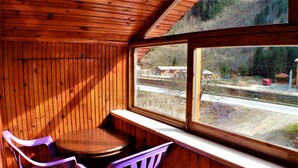 A wooden cabin with a dining area featuring two purple chairs and a round table. - Yaren Otel (Çaykara)