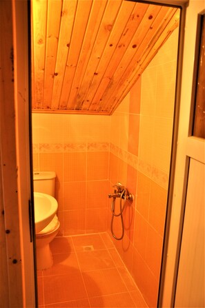 A small, enclosed bathroom with a wooden ceiling, a toilet, and a shower area. - Yaren Otel (Çaykara)