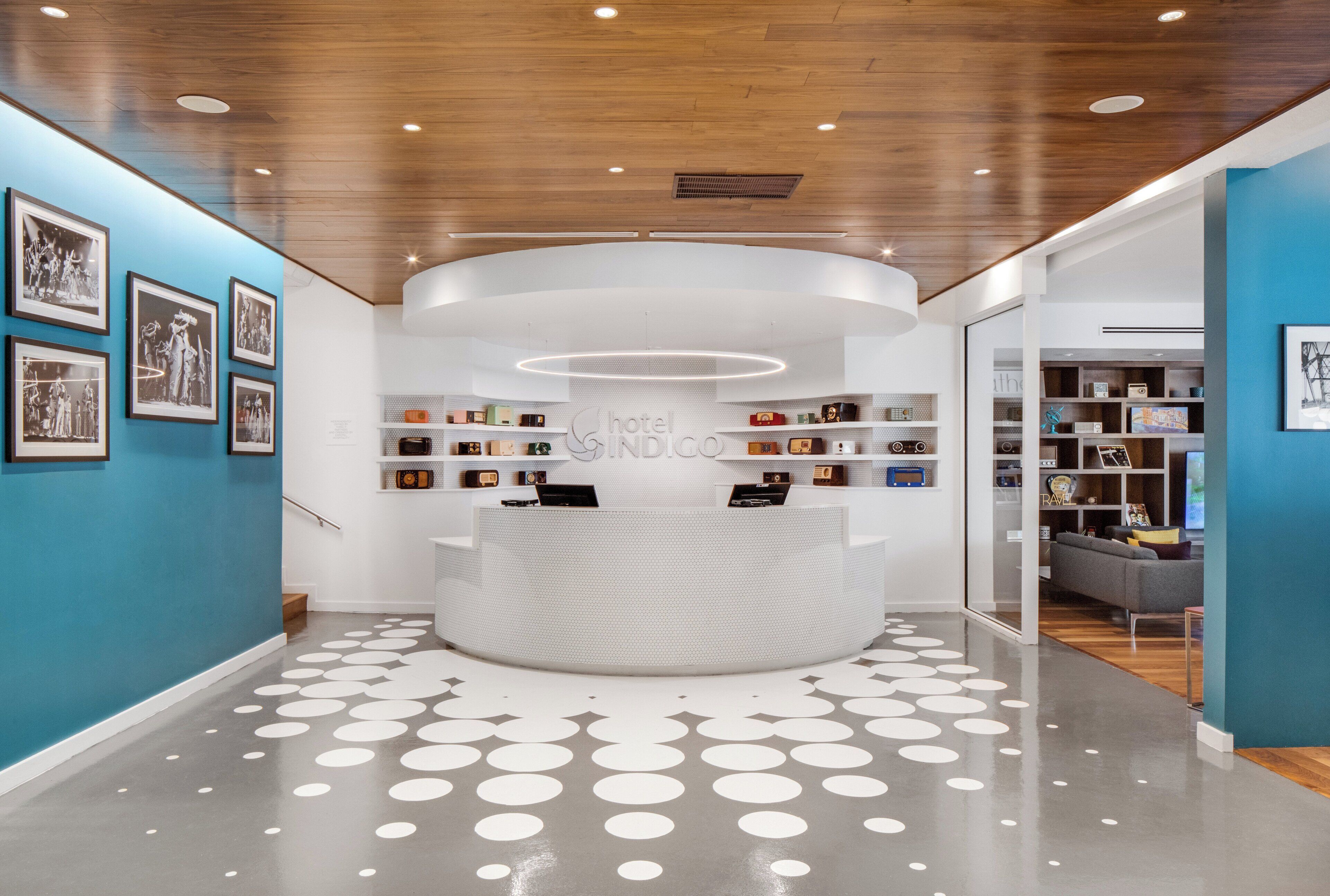 A reception desk with a modern design, surrounded by a blue wall with framed photographs.