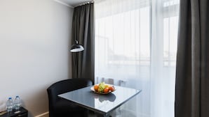 A hotel room with a glass table, a black chair, a fruit bowl, and a lamp. - centerroom Muenchen City (Munich)