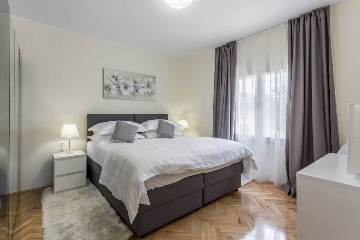 Une chambre à coucher moderne avec un grand lit, des tables de chevet, une commode et un tableau au mur.