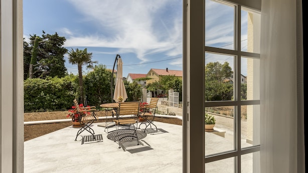 Une terrasse avec une table et des chaises, un pot de fleurs et un banc.