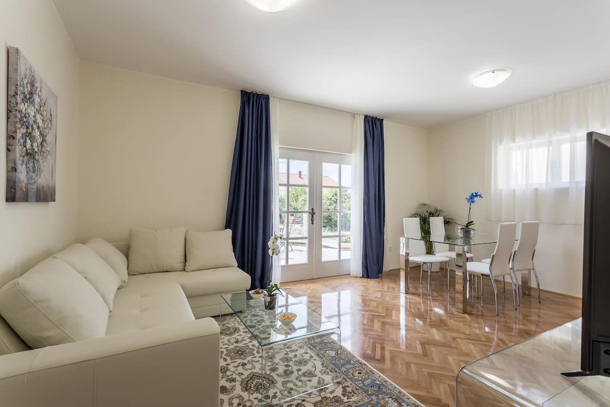 Un salon moderne avec un canapé, une table basse en verre et un coin repas comprenant des chaises et une table.