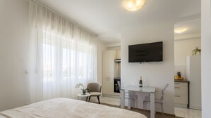 Une chambre d’hôtel moderne dotée d’un grand lit, d’un bureau avec une chaise, d’un téléviseur à écran plat et d’une petite table sur laquelle est posé un vase.