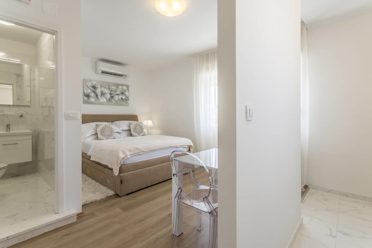Une chambre moderne avec un lit, une table de chevet et une chaise transparente.