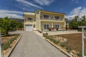 Un immeuble de deux étages avec une allée menant à une entrée fermée par un portail.