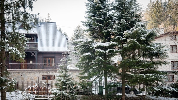 Un edificio de madera con un balcón, rodeado de árboles cubiertos de nieve y una valla.