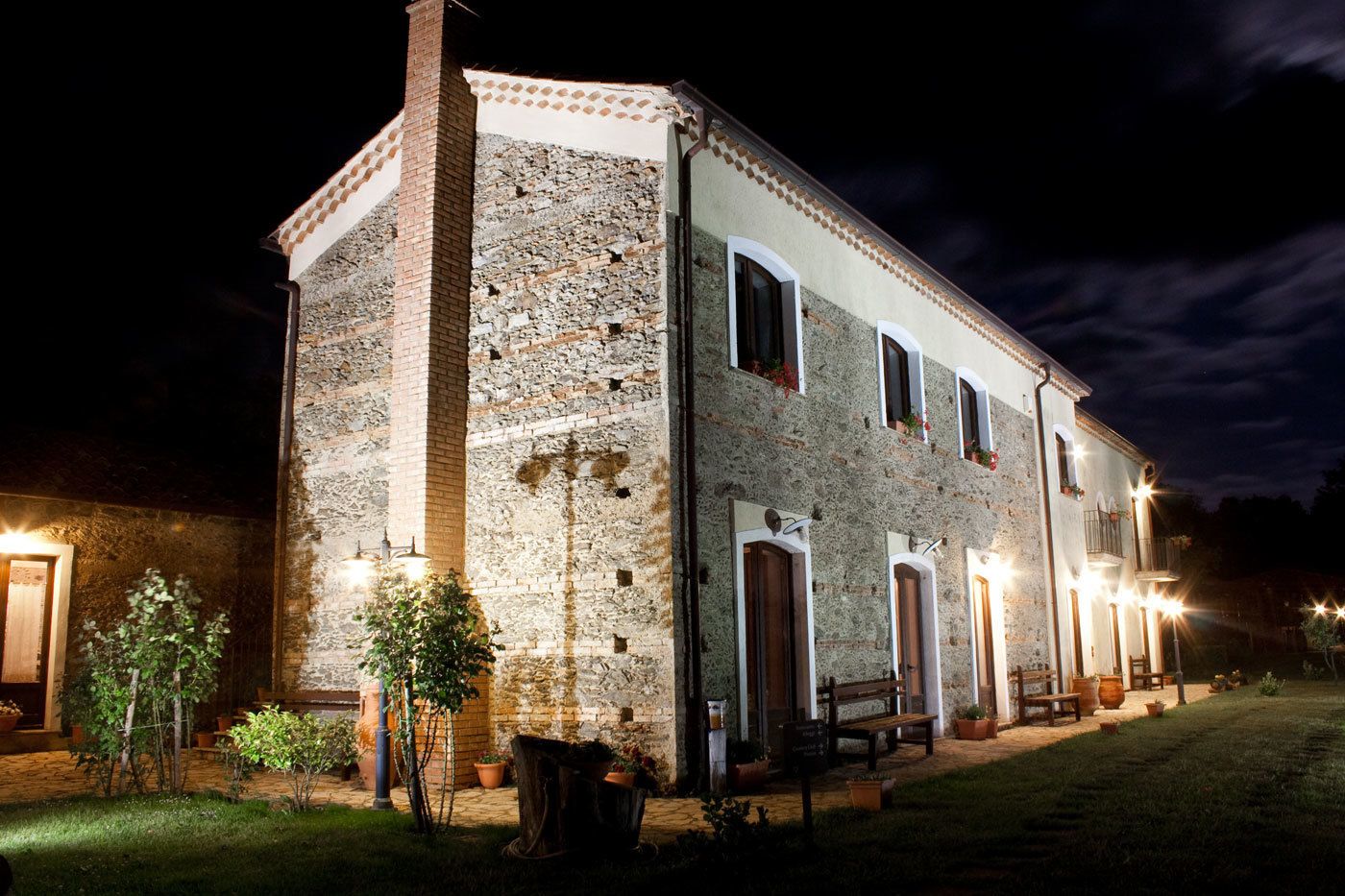 A stone building with multiple doors and windows, illuminated by exterior lights.