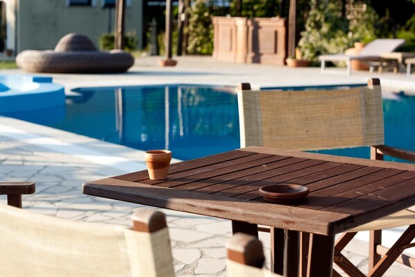 Una mesa y silla de madera junto a una piscina con vista despejada al agua.