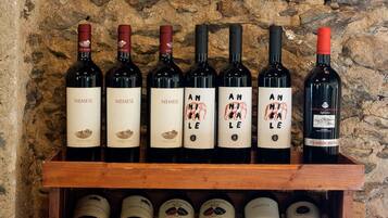 A wooden wine rack holding several wine bottles against a stone wall background.