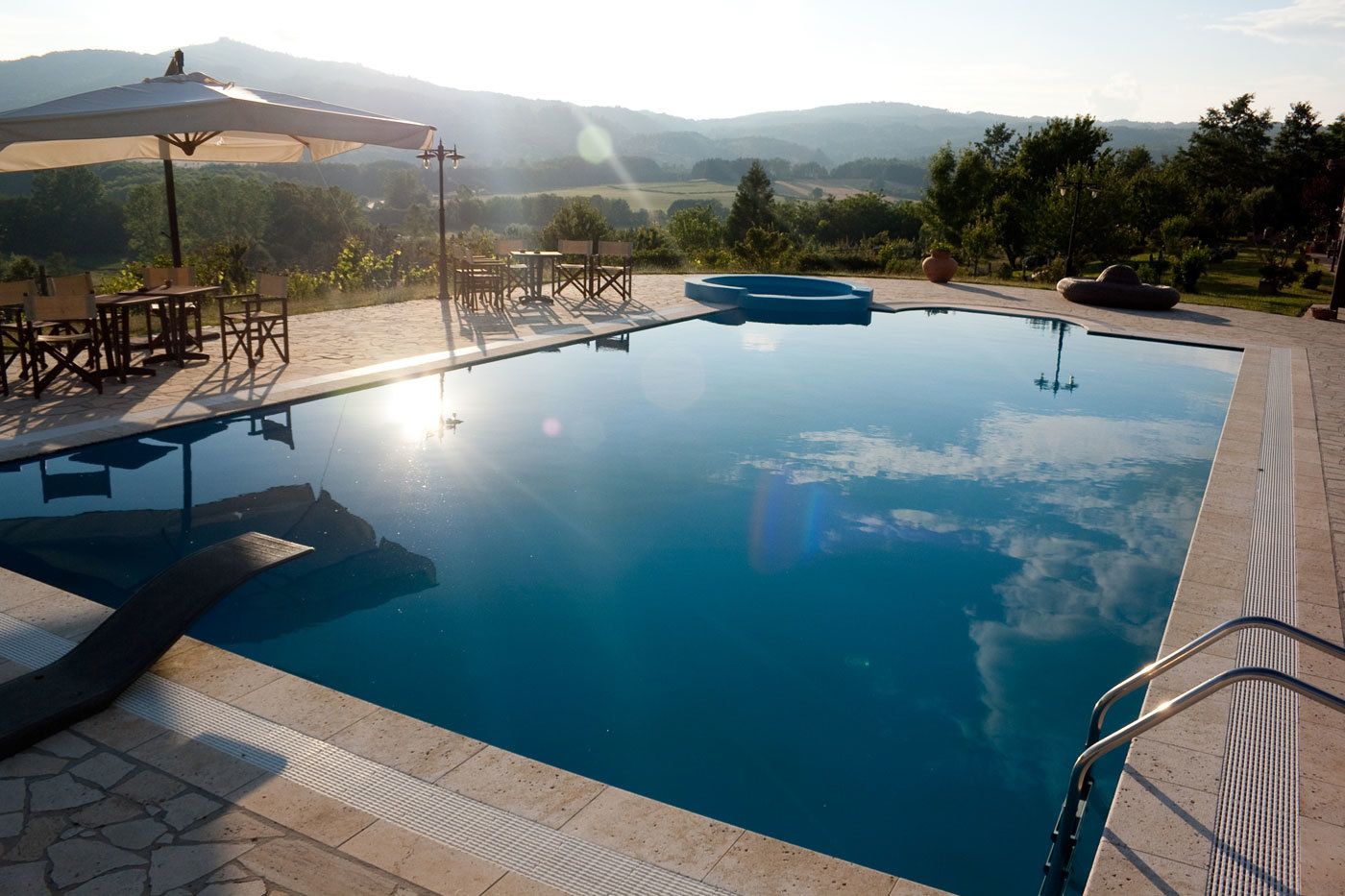 Une piscine avec vue sur les montagnes, un espace extérieur aménagé et une pergola.