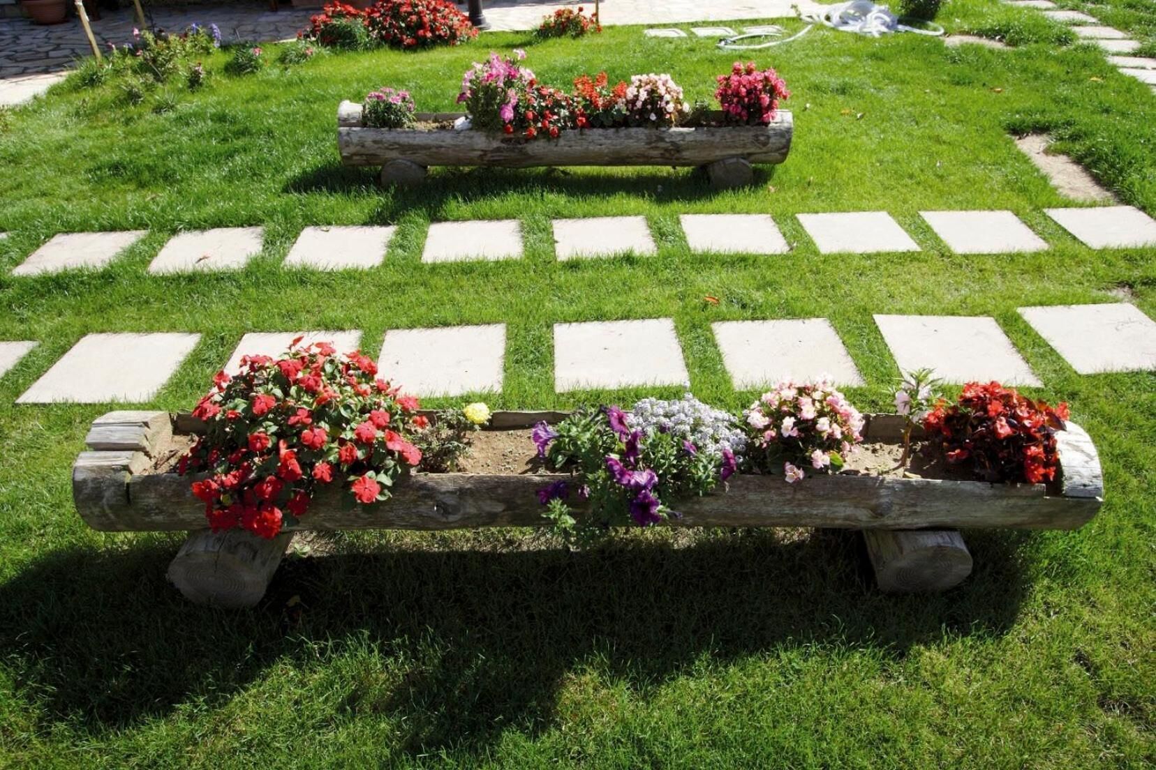 En trädgård med en träbänk och blomsterarrangemang.