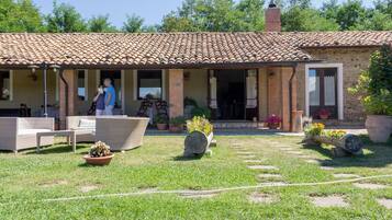 Una casa rústica con techo de tejas, mobiliario exterior y plantas en macetas.