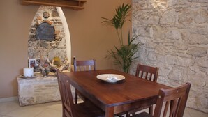 Un comedor con chimenea de piedra, mesa de madera, sillas y una planta en maceta.