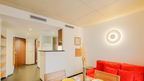 A modern hotel room with a dining area, a red sofa, and a vase with flowers.