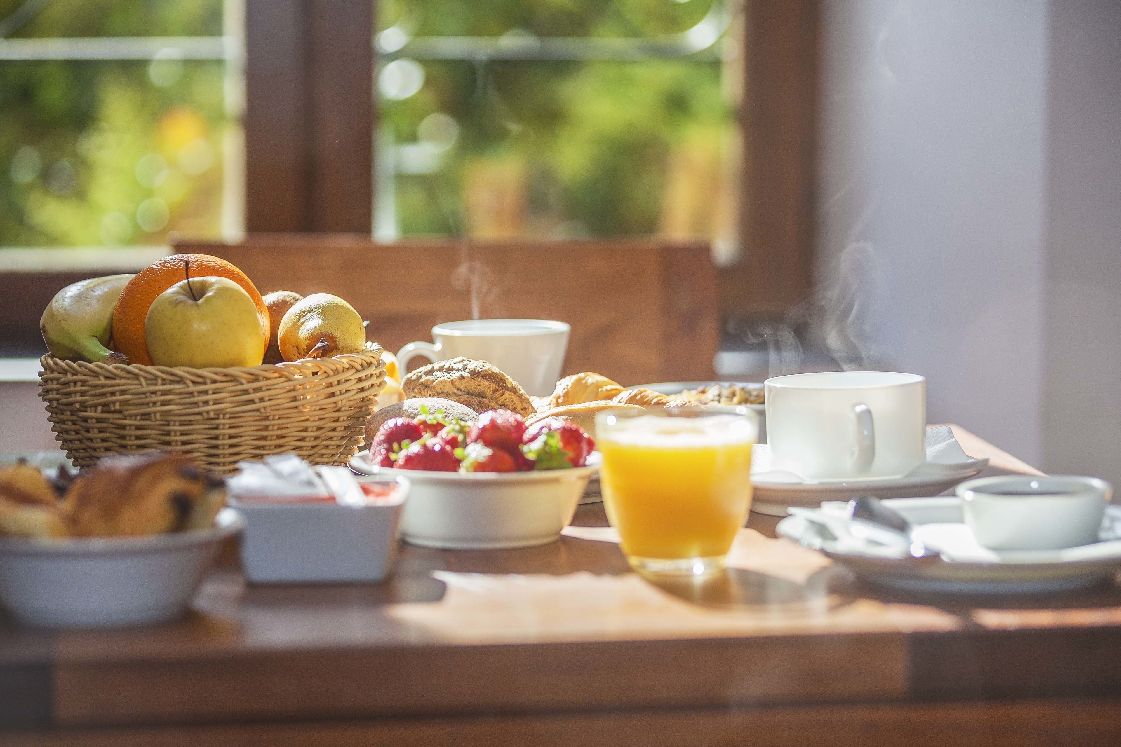 Taula de matí amb una cistada de fruites, croissants i una tassa de cafè.
