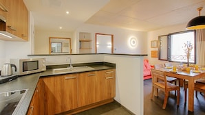 A modern kitchen with wooden cabinets, a built-in microwave, and a dining area with a wooden table and chairs.