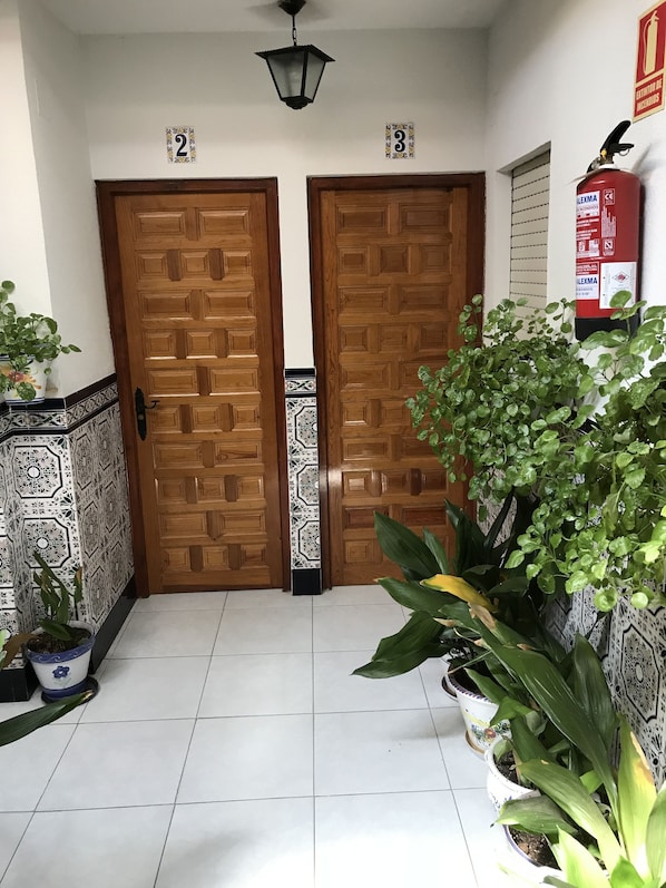 Un pasillo con dos puertas de madera, numeradas 2 y 3, y un extintor en la pared.