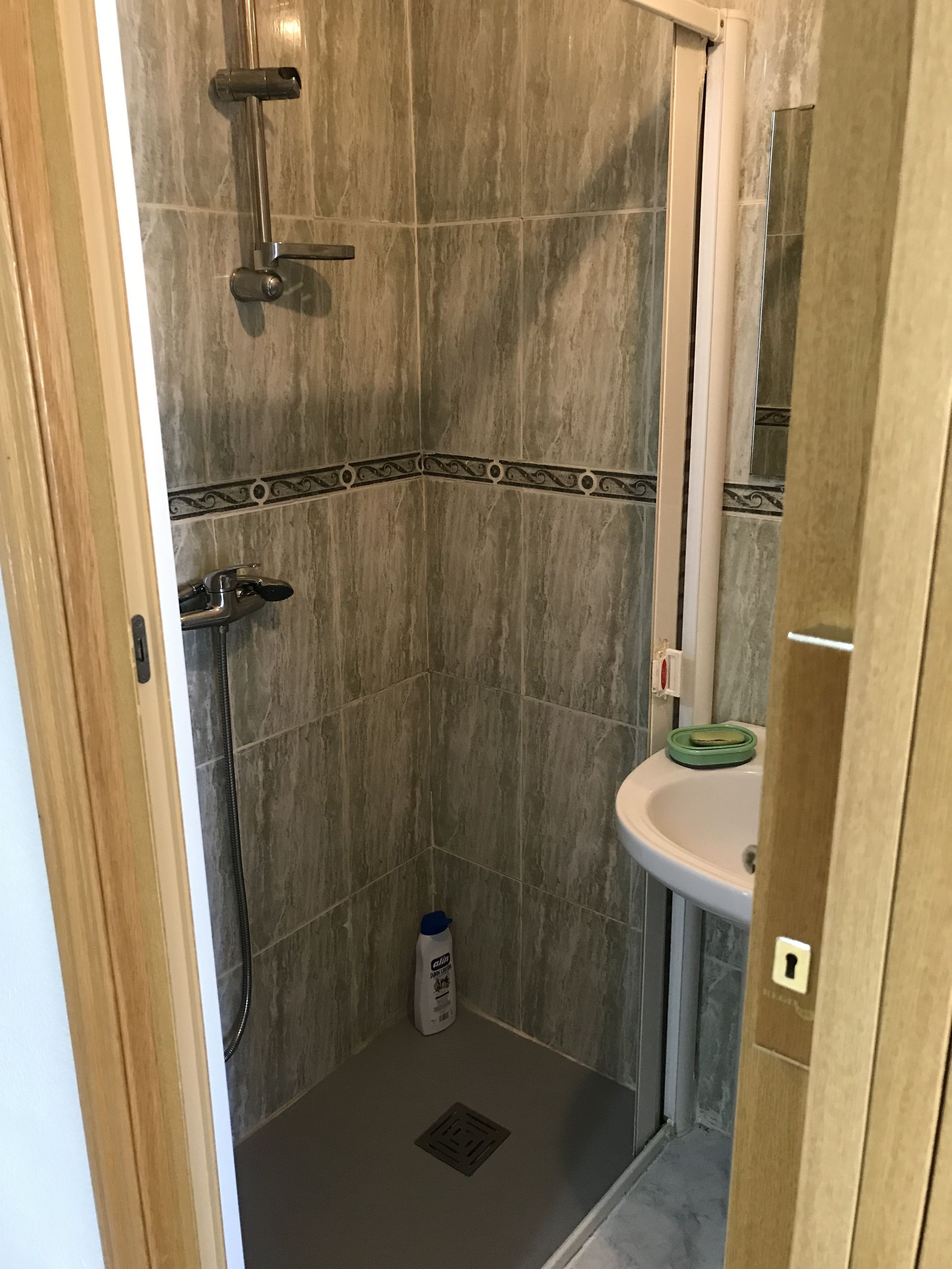 A shower with a handheld showerhead, a handheld showerhead, and a handheld showerhead.
