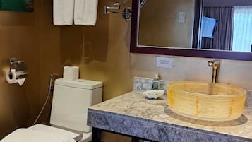 Un baño con lavamanos de mármol, inodoro, toallero y espejo.