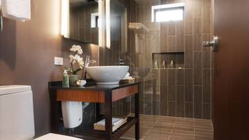 A modern bathroom with a white toilet, a large sink, and a shower area.