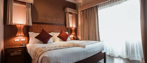 A large bed with a wooden headboard, two bedside lamps, and a nightstand with a lamp.