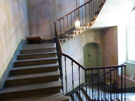 Una escalera de mármol con barandilla de madera y un candelabro en la parte superior.