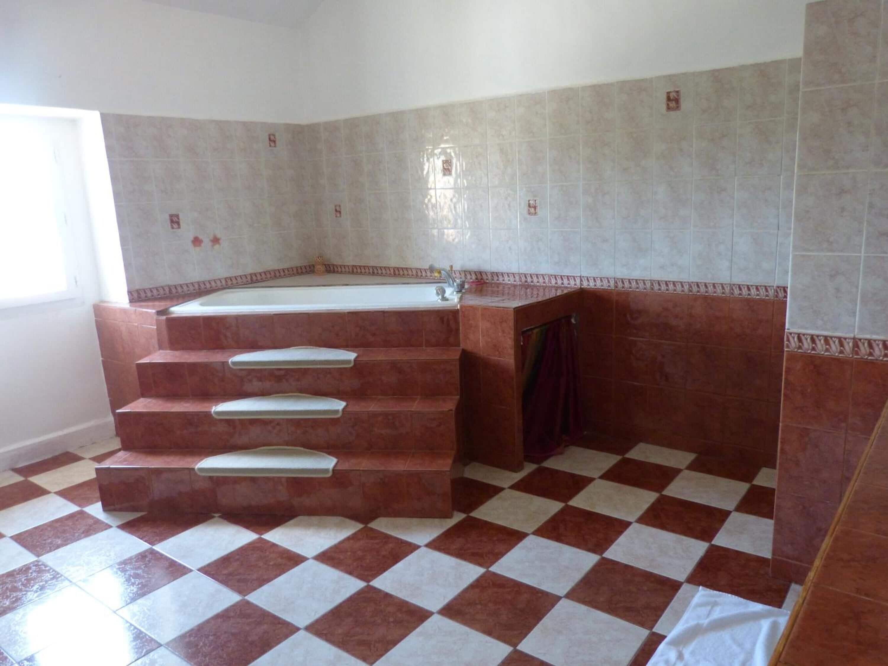 A bathroom with a large bathtub, a shower, and a tiled floor.