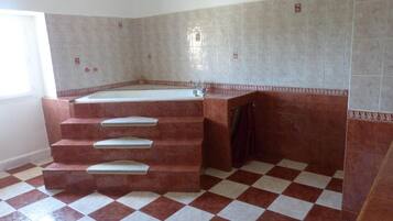 A bathroom with a large bathtub, a shower, and a tiled floor.