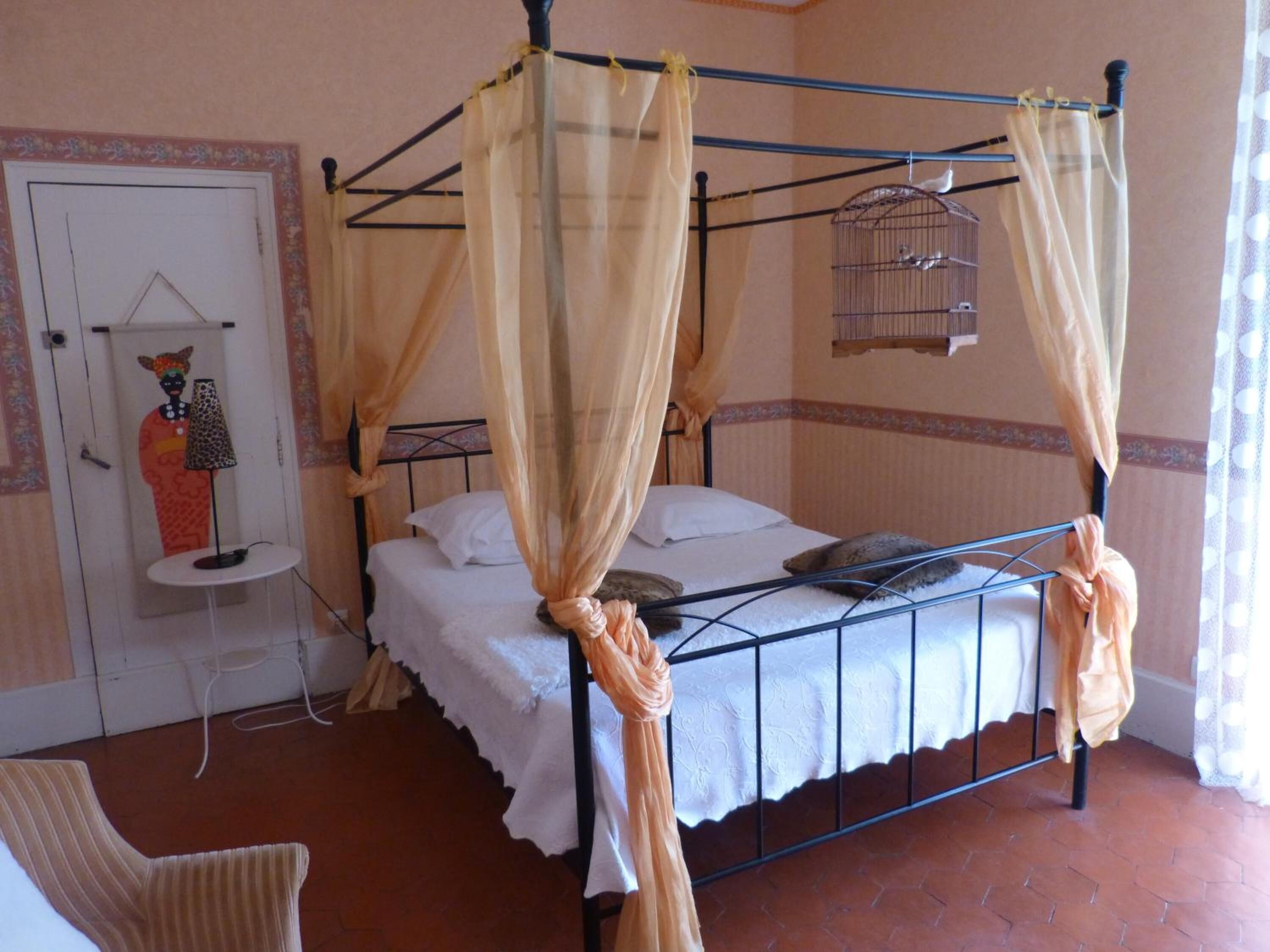 Un letto a baldacchino con tende, una piccola comodino e una sedia.