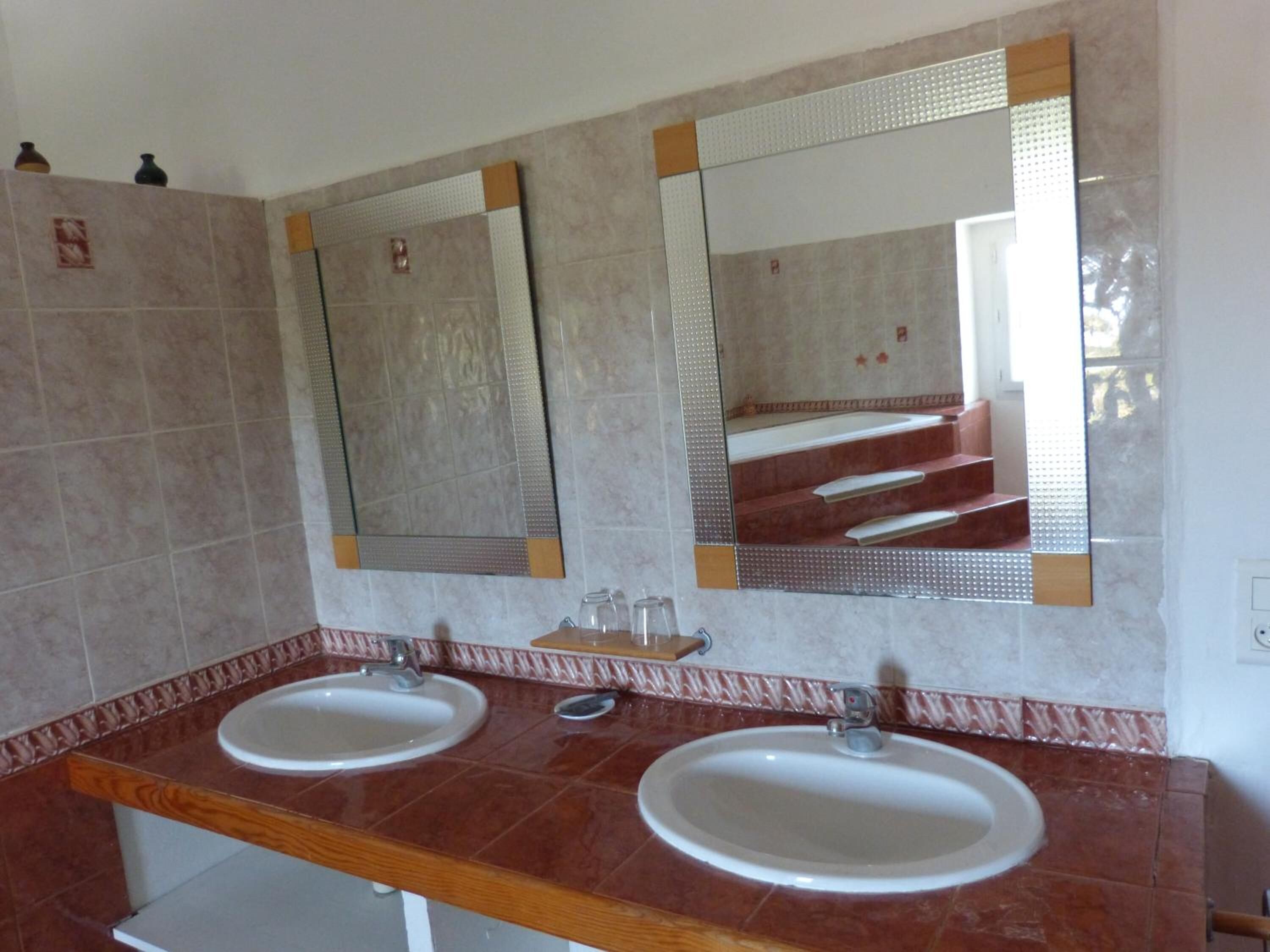 A bathroom with two sinks, mirrors, and a wooden countertop.