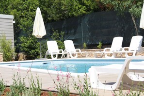 A swimming pool with white lounge chairs and a covered umbrella. - Mobile Homes Peskera (Medulin)