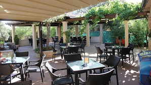 An outdoor patio area with tables and chairs, covered by a pergola with vines. - Mobile Homes Peskera (Medulin)