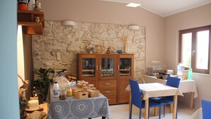 A dining area with a stone wall, wooden cabinet, and blue chairs. - Mobile Homes Peskera (Medulin)