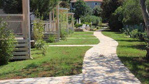 A pathway leading to a building with a covered outdoor area and a garden. - Mobile Homes Peskera (Medulin)