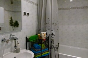 A bathroom with a sink, mirror, shower, and towel rack.
