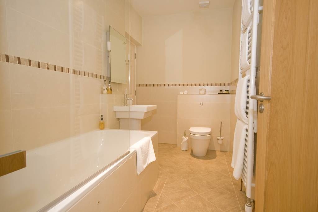 A bathroom with a bathtub, sink, toilet, and a towel rack.