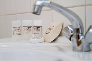 A bathroom sink with three bottles of soap and a soap dish. - Stephen Margolis Resort (Harare)