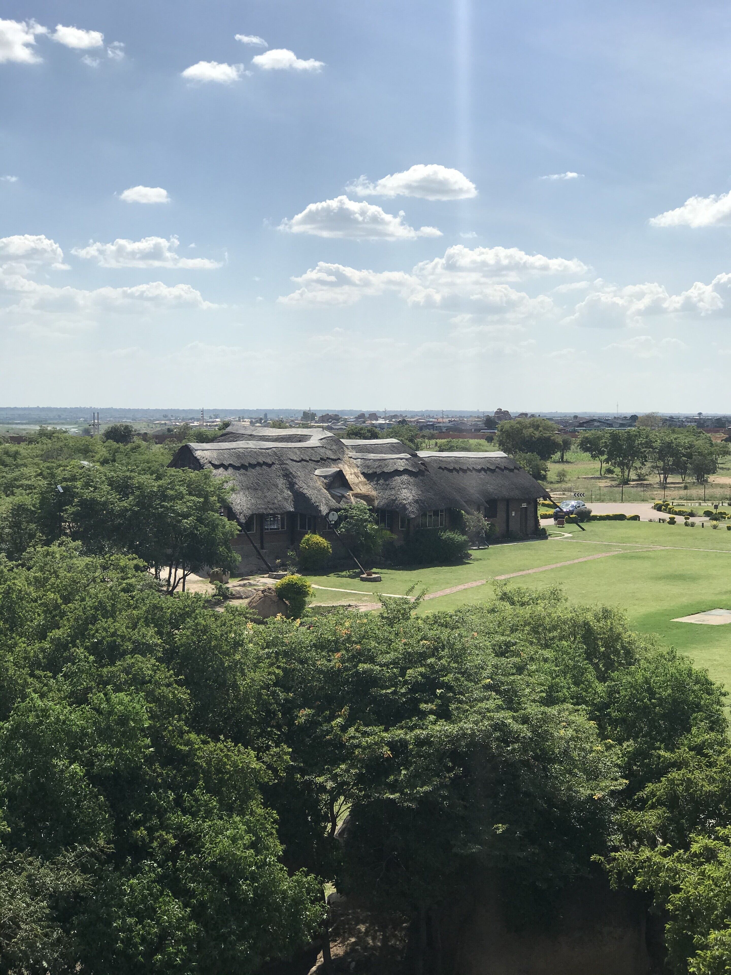 A thatched-roof building surrounded by lush greenery and a well-maintained lawn.