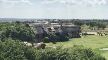 A thatched-roof building surrounded by lush greenery and a well-maintained lawn.
