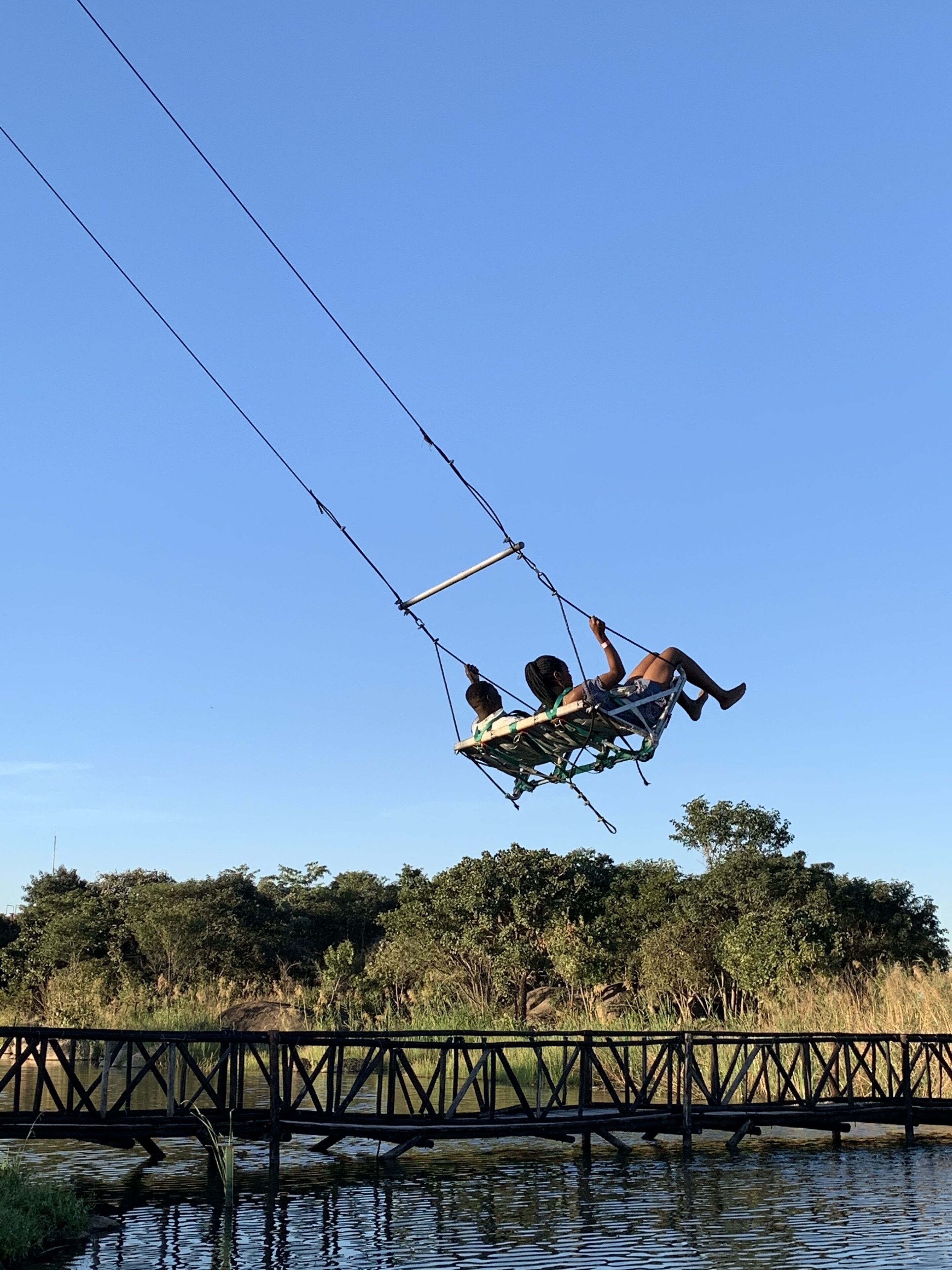 Un puente sobre el agua, con una atracción de tirolesa al fondo.