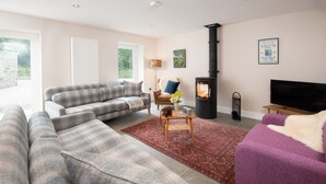 A living room with a sofa set, a coffee table, a fireplace, and a television. - Mill House (Crieff)