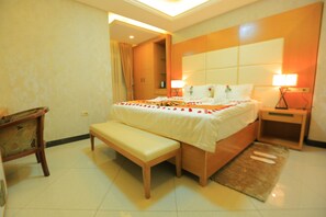 A hotel room with a large bed, bedside tables, a bench, and a wooden wardrobe. - Haven Hotel (Addis Ababa)