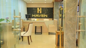 A reception area with a marble reception desk, a reception sign, a reception computer, and a white chair. - Haven Hotel (Addis Ababa)