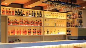 A bar area with shelves of liquor bottles, a counter, and bar stools. - Haven Hotel (Addis Ababa)