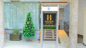 A hotel entrance with a Christmas tree, a reception desk, and a staircase leading to the upper floors. - Haven Hotel (Addis Ababa)