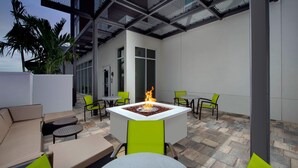 An outdoor patio with a fire feature, seating, and a glass-enclosed area. - SpringHill Suites by Marriott Punta Gorda Harborside (Punta Gorda)