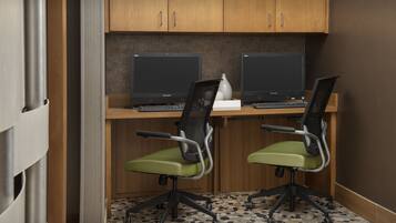 Un espace de travail comprenant deux bureaux, chacun équipé d’un écran d’ordinateur, d’un clavier et de chaises de bureau vertes.