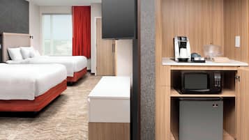Habitación de hotel con dos camas, televisión, cafetera, microondas y refrigerador.